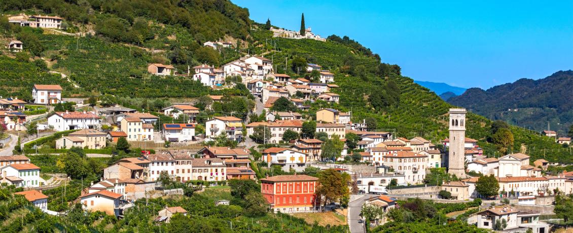 A small town on a hilltop surrounded by vineyards in Conegliano, Italy.